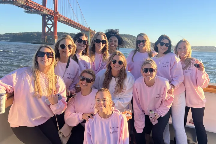 Bachelorette party group in matching pink sweatshirts aboard Wine Therapy with Golden Gate Bridge, San Francisco Bay