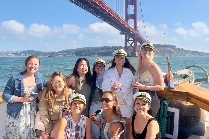 Group of women in captain's hats aboard Wine Therapy with Golden Gate Bridge, San Francisco Bay